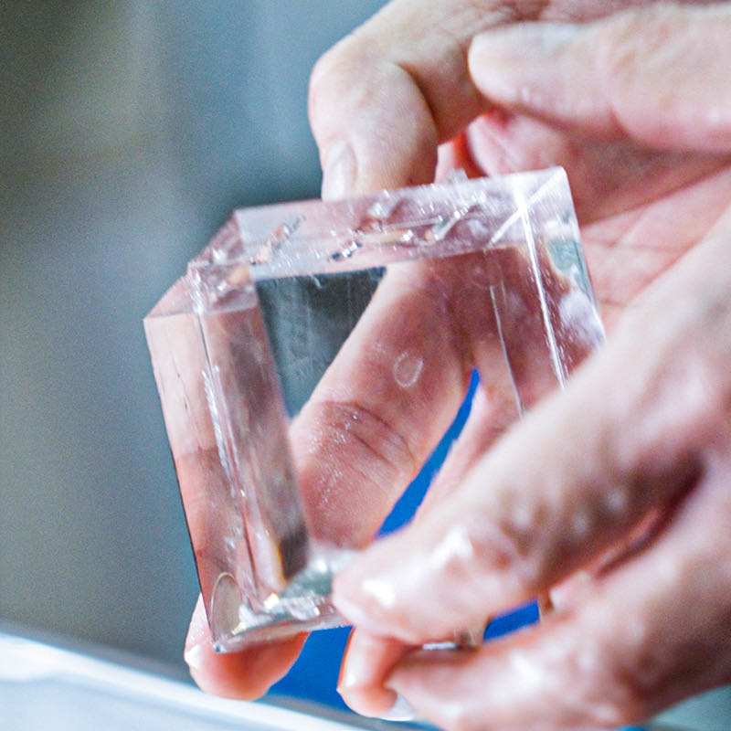 A perfectly shaped clear ice cube held in hands