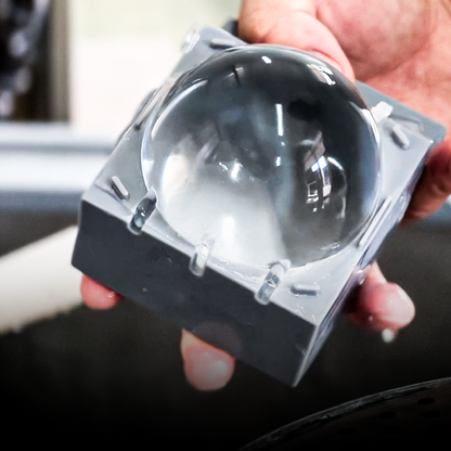 A crystal-clear ice sphere with the silicone mold half-opened