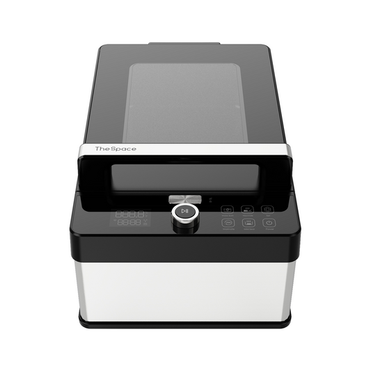 Black and silver device with a glass lid and control panel on a white background